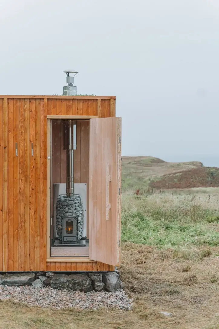 Ardna sauna entrance with a glazed door and timber cladding